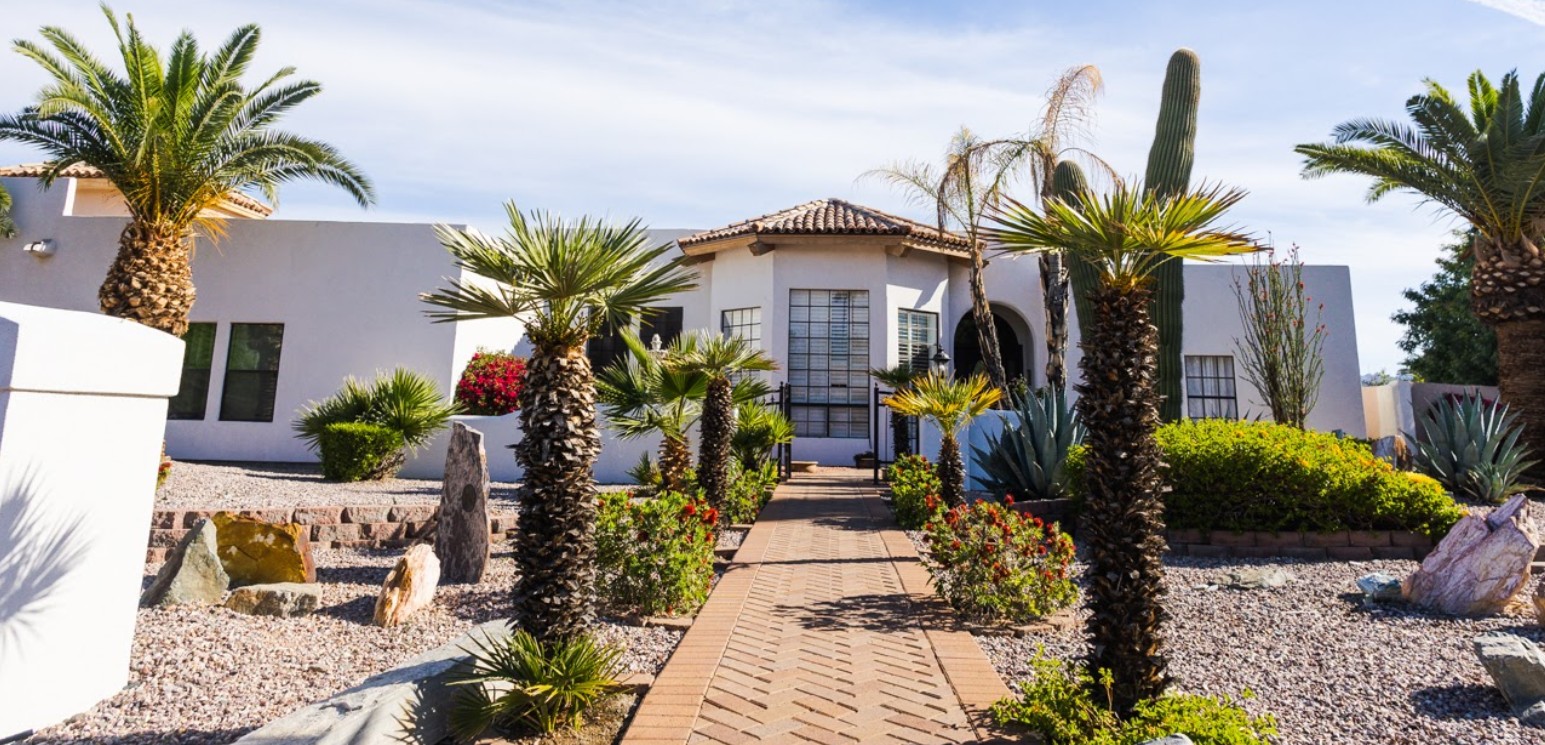 Assisted living home exterior with desert landscaping, palm trees, and accessible walkway entrance