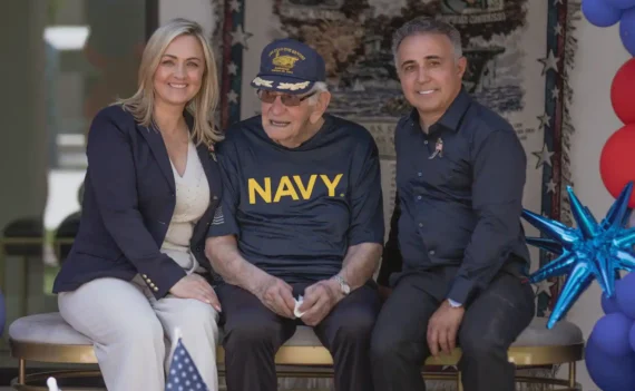 Senior resident wearing a Navy shirt celebrating with staff during a patriotic event at Torbrook Assisted Living in Scottsdale, Arizona, with American flags and decorations
