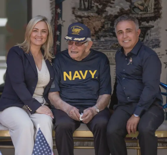 Veteran Celebration at Torbrook Assisted Living in Scottsdale AZ Senior resident wearing a Navy shirt celebrating his 100th birthday at Torbrook with two others.