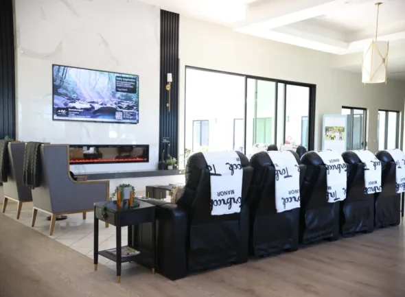 Modern assisted living lounge with recliner seating, fireplace, and TV entertainment area for seniors